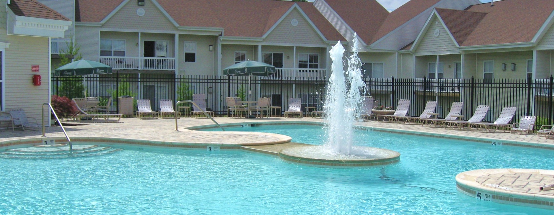 Large swimming pool with fountain surrounded by lounge chairs